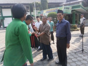 Warek II, Kepala Biro AUAK beserta jajaran panitia menyerahkan secara simbolis perlengkapan dan atribut KKN dalam acara pelepasan peserta KKN.